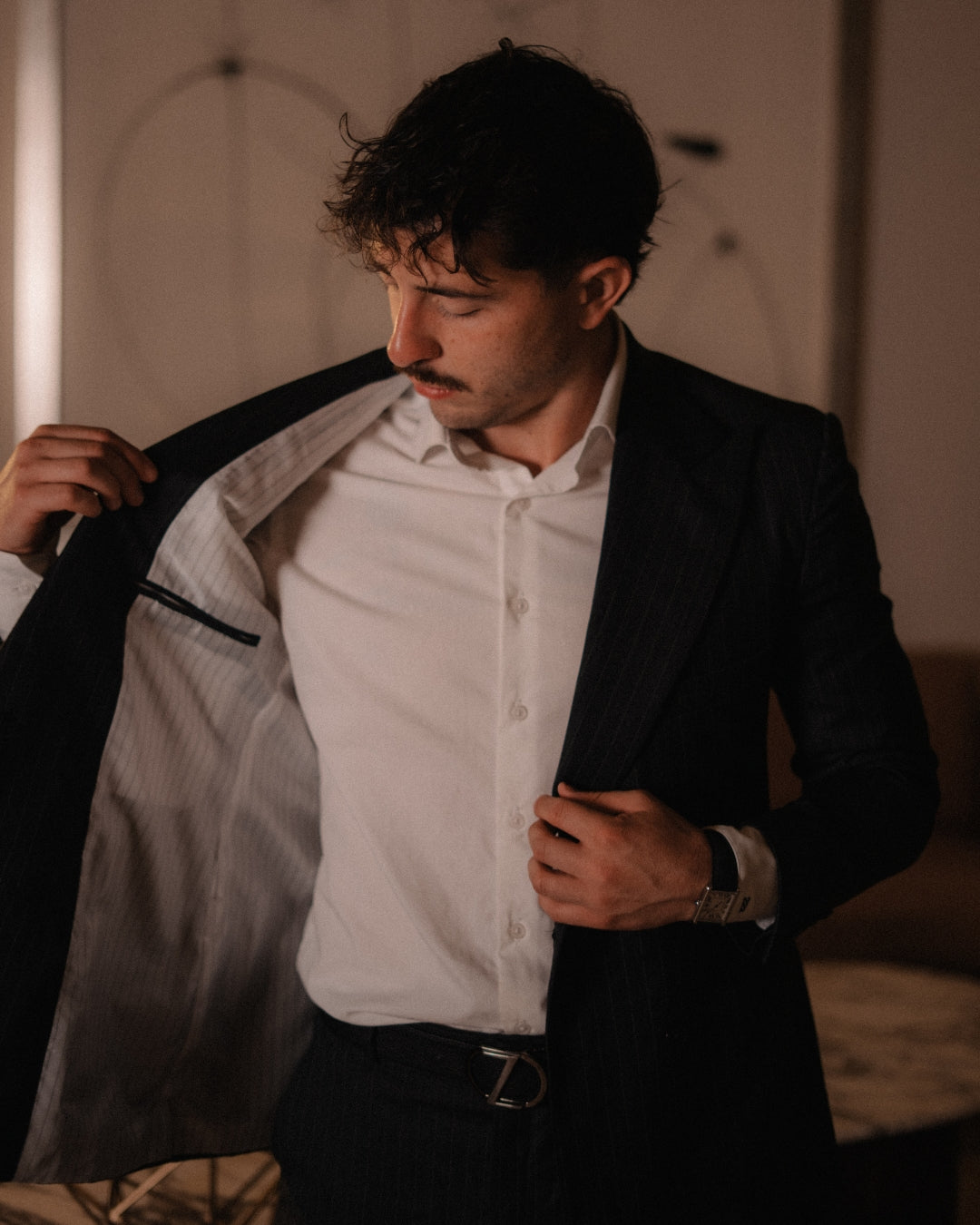 Este traje de raya diplomática en tono oscuro, acompañado por una camisa blanca impecable, encarna la elegancia clásica con una presencia moderna.