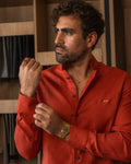 La camisa roja de botonadura clásica, realzada por el bordado personalizado, transmite fuerza, identidad y refinamiento.